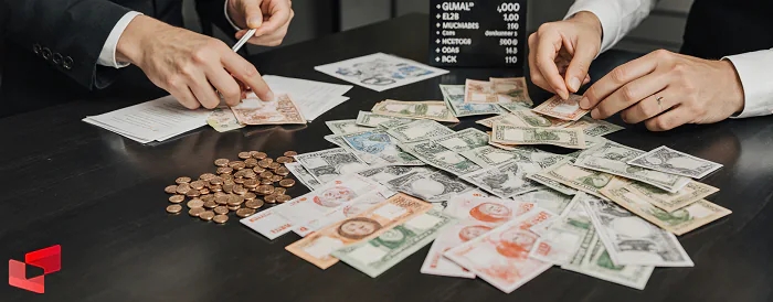 سکه‌های طلا و اسکناس‌های ارز خارجی بر روی میز صرافی در کرمان